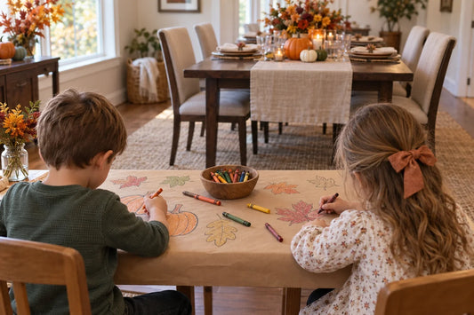 Two children color autumn outlines on a kraft-paper runner at a side table beside a set Thanksgiving dining table