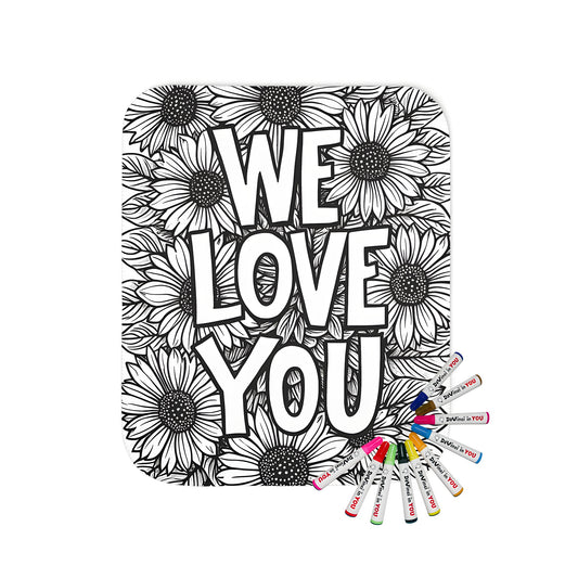 A cozy blanket featuring a beautiful black and white floral coloring page design with sunflowers, dahlias, and gerbera-like blooms, and the bold text 'WE LOVE YOU' in vibrant colors. Perfect for adding a touch of whimsy to any room.