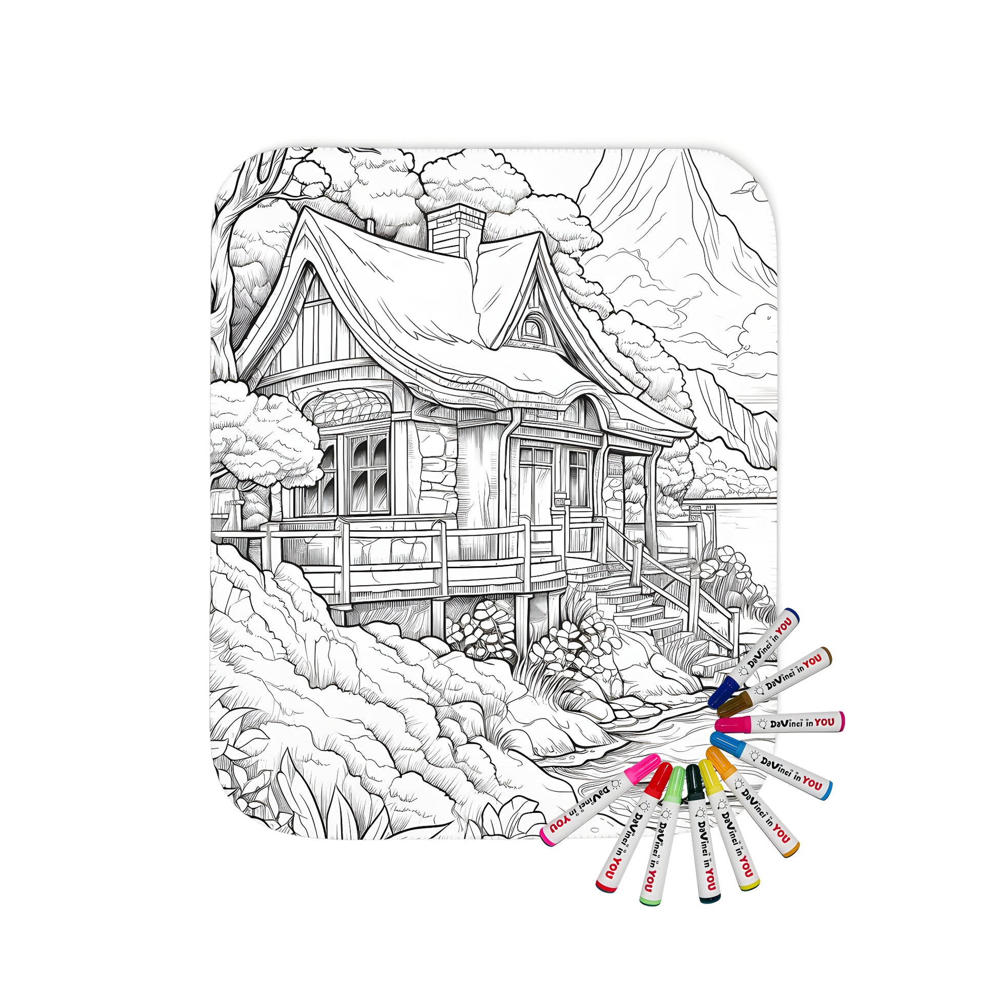 Blanket with nature scene illustration, rustic cabin by river, surrounded by trees and mountains, colorful fabric markers included