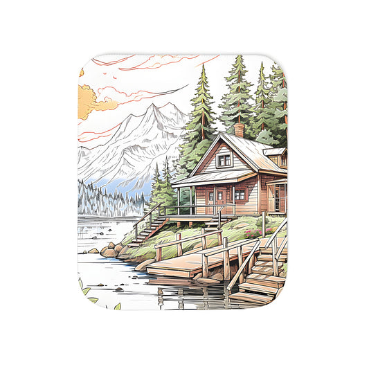 A cozy blanket featuring a serene wooden cabin scene, surrounded by a peaceful lake, pine trees, and majestic mountains at sunset.