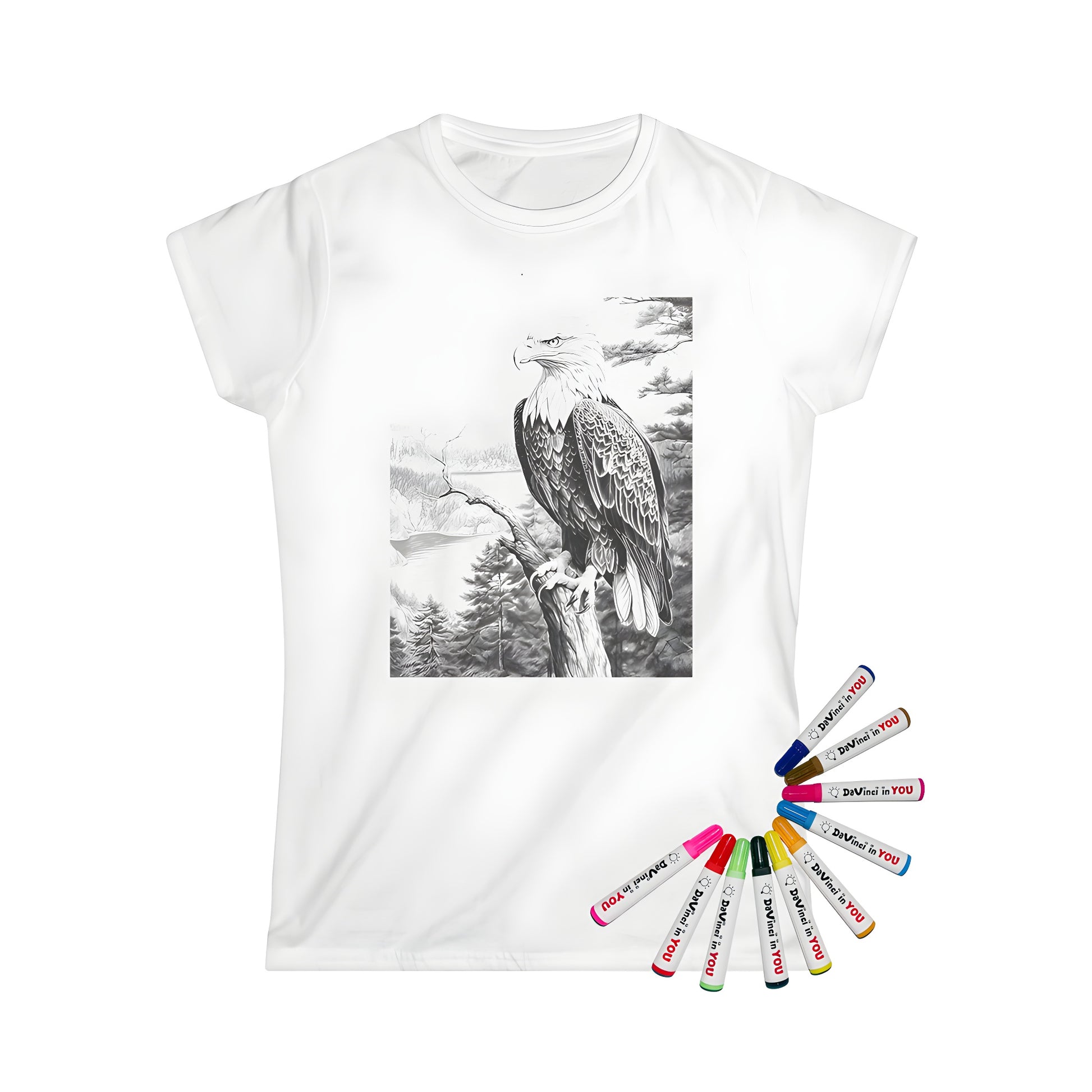 A detailed drawing of an eagle perched on a tree branch with mountains and a forest in the background is printed on a women's t-shirt using fabric markers