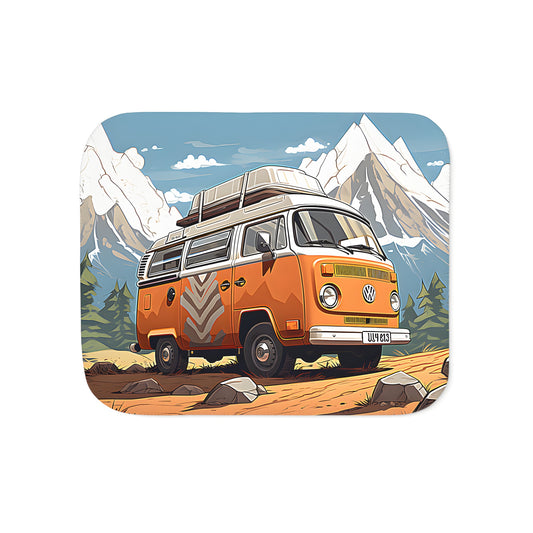 A colorful vintage-style van blanket with a unique design featuring a scenic mountainous landscape and a classic vehicle parked among rocks and trees under a clear blue sky.