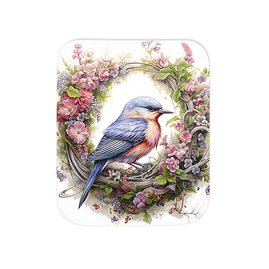 Colorful blanket featuring a vibrant blue bird illustration within a floral wreath design, crafted in soft pastel hues